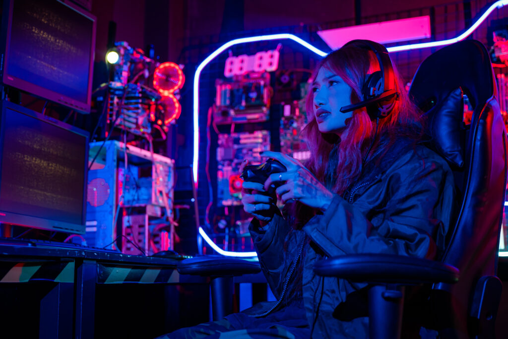 young-woman-wear-gaming-headphones-playing-esports-games-console-gaming-room-gamer-using-joystick-controller-virtual-tournament-plays-online-video-game-with-computer-neon-lights